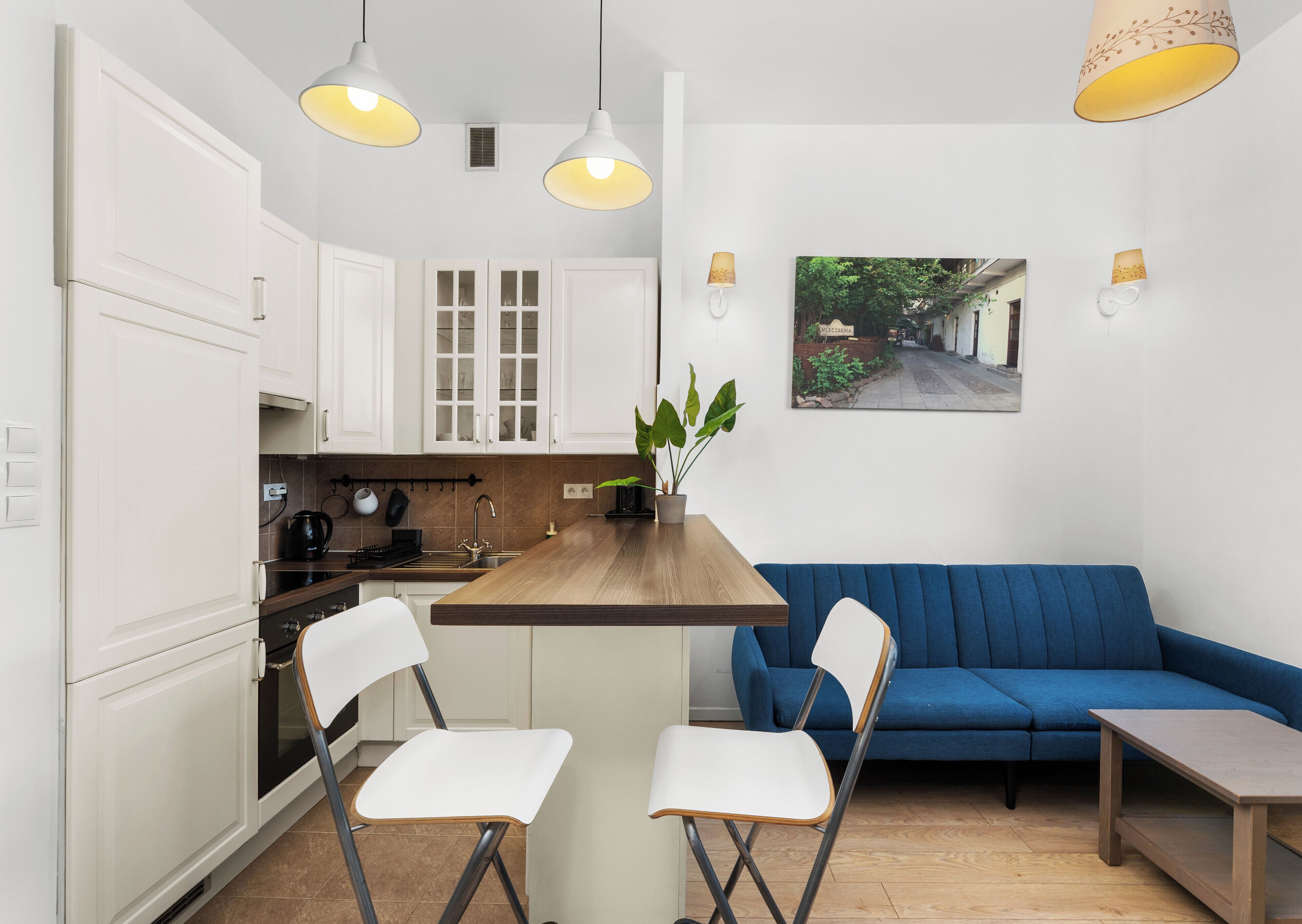 Una cocina moderna con armarios blancos, una isla de madera y dos sillas blancas.