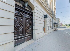 A building with a large, ornate wooden door, a paved sidewalk, and a street view. - Kazimierz Riverside Charming Apartment (Kraków)