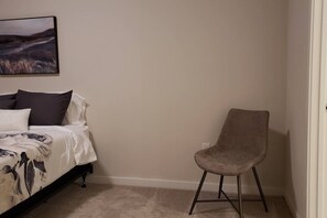 A bedroom with a bed, a chair, and a painting on the wall.
