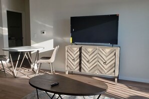 A living room with a round table, a sofa, a TV, and a cabinet.