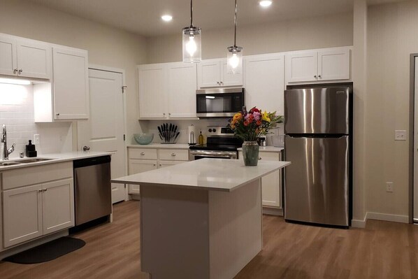 A modern kitchen with white cabinetry, stainless steel appliances, and a central island.