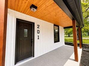Een modern gebouw met een houten plafond, een zwarte deur en het getal '201' op de muur.