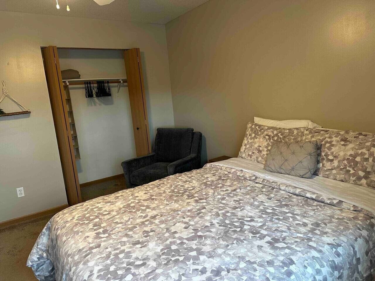 A bedroom with a bed, a chair, a closet, and a coat rack.