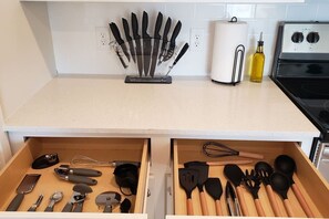 A kitchen with a knife block, paper towel holder, and a bottle of oil on the counter.