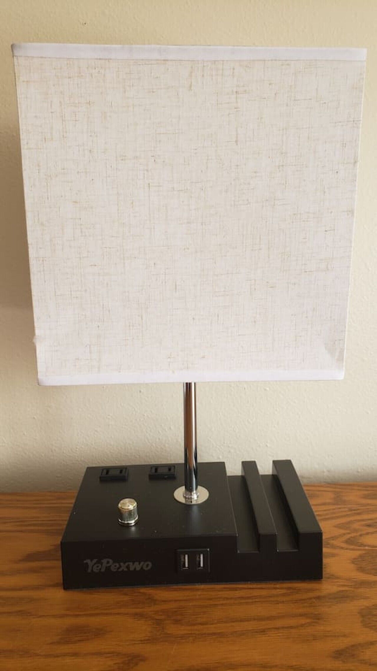 A table lamp with a rectangular shade on a black base with a brand name.