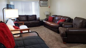 A living room with a brown leather sofa, a black armchair, and a wooden coffee table.