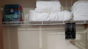 A storage closet with shelves, a blue plastic bin, and a first-aid kit.