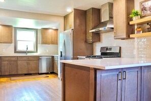 Une cuisine moderne avec des meubles en bois, des appareils électroménagers en acier inoxydable et un grand îlot central.