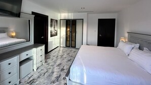 Une chambre d’hôtel avec un lit, un bureau, une armoire et une porte.