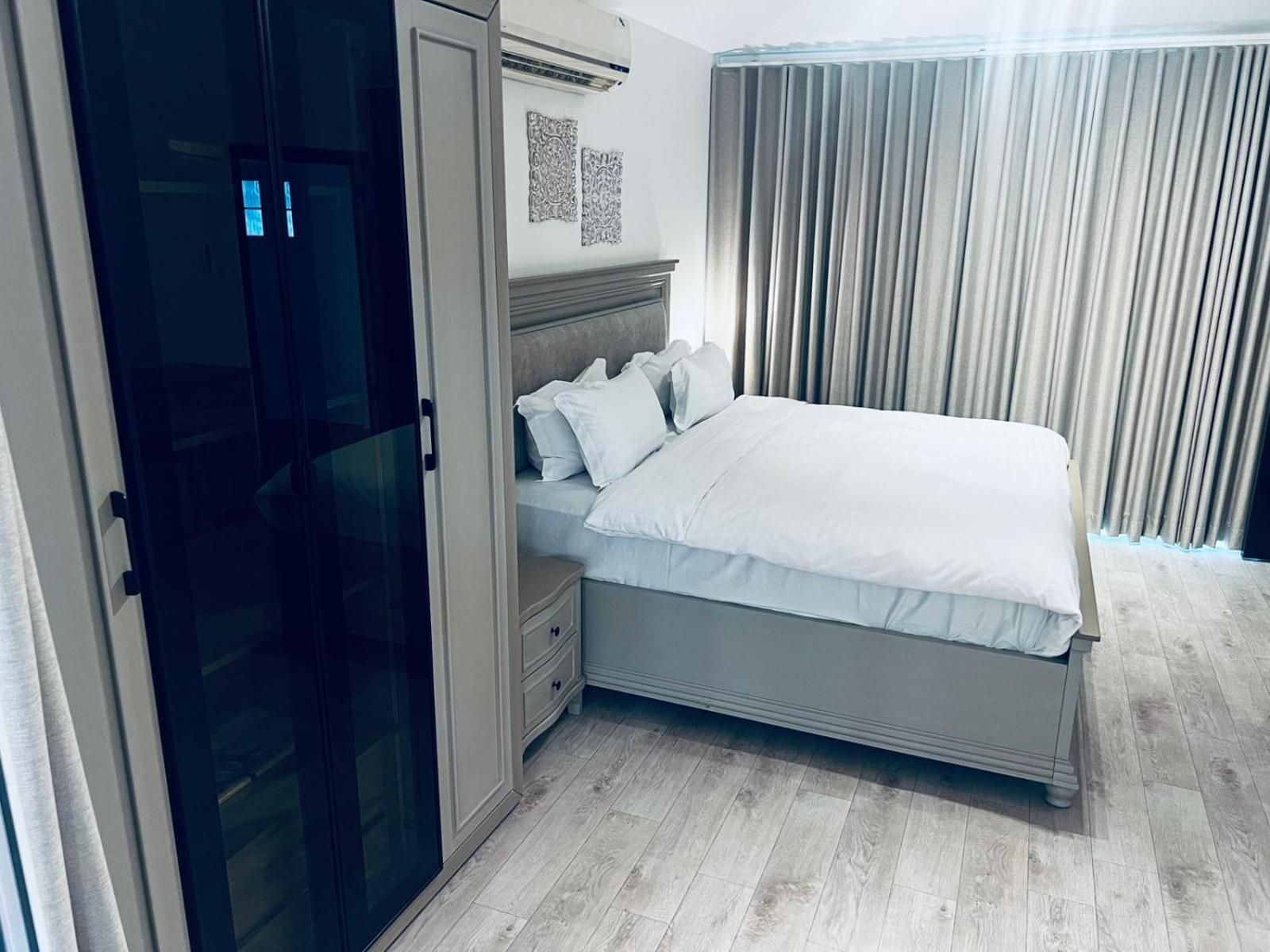 Ein Schlafzimmer mit einem Bett, einem Kleiderschrank und einem Fenster mit Vorhängen.
