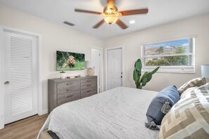 A bedroom with a bed, a ceiling fan, a television, a dresser, and a window with blinds. - THE SEA MIST (Lauderdale-by-the-Sea)