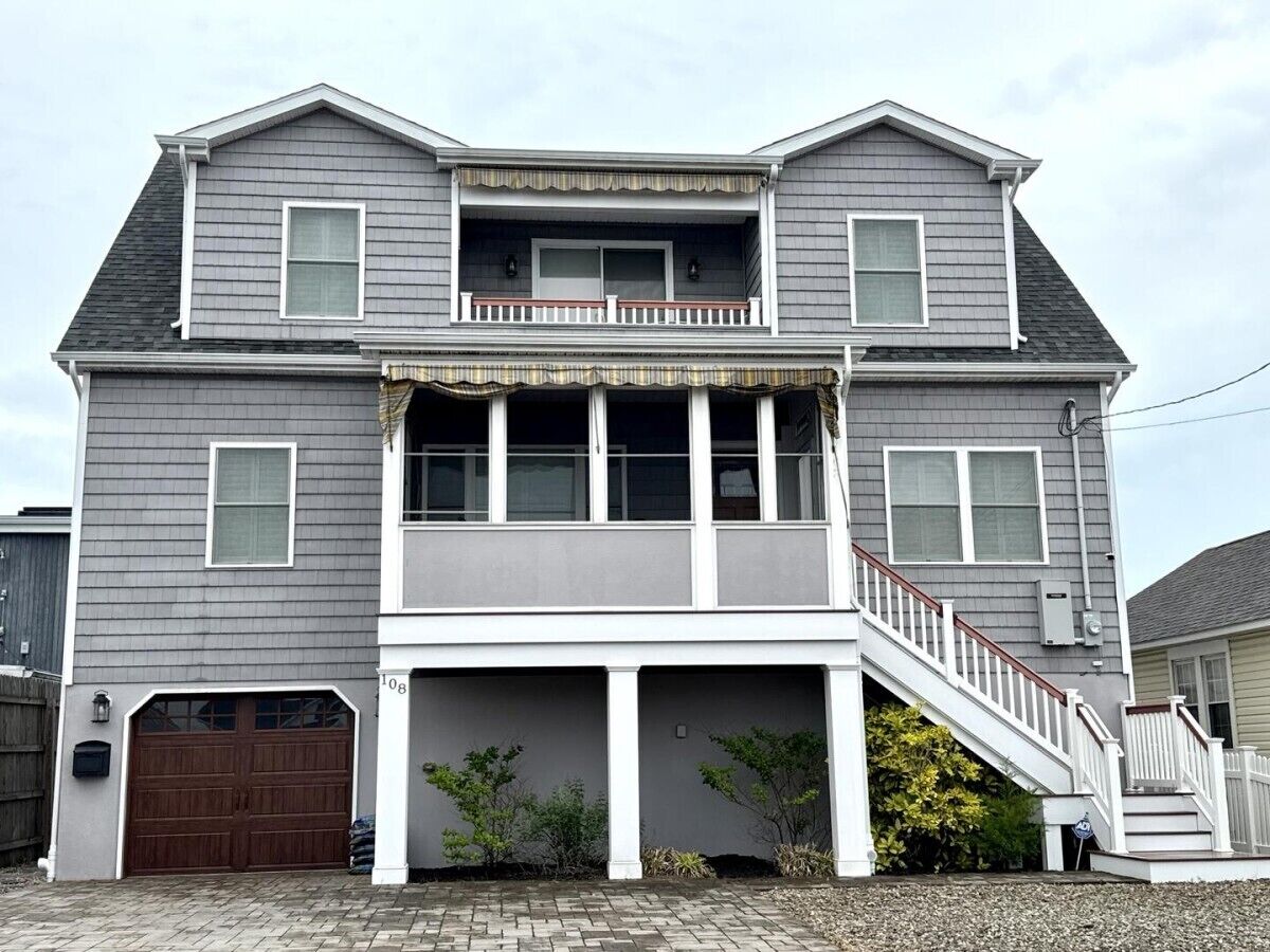A two-story house with a front porch, a garage, and a staircase leading to the upper level.
