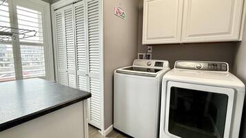 A laundry room with a washing machine, dryer, and a drying rack.