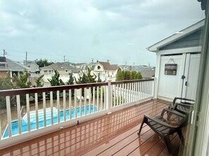 Une terrasse en bois avec une piscine, une clôture blanche et un banc.