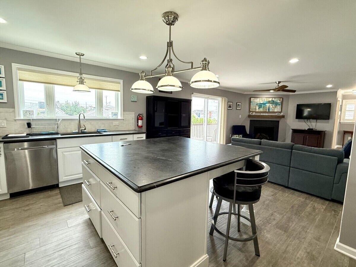 A modern kitchen with a central island, stainless steel appliances, and pendant lighting.