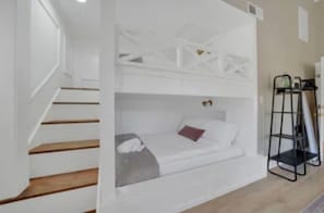 A room with a bunk bed, a ladder, and a staircase.