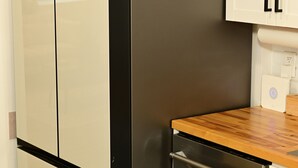 A kitchen with a stainless steel refrigerator, a wooden countertop, and white cabinets. - Wynter Luxe  (Peachtree City)