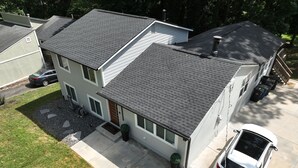 A two-story house with a grey roof, a driveway, and a white car parked in the driveway. - Wynter Luxe  (Peachtree City)