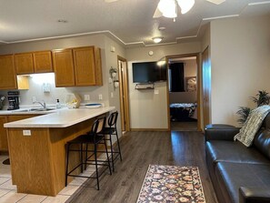 Un espacio habitable compacto con cocina, una mesa de comedor con sillas, un sofá y un tapete estampado.