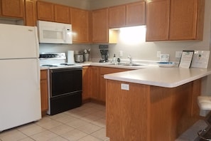 A kitchen with wooden cabinets, a white refrigerator, a microwave, a stove, and a sink.