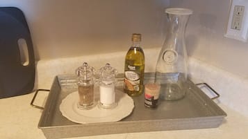 A kitchen counter with a tray holding various items including a bottle of extra virgin olive oil, a glass bottle, salt and pepper shakers, and a small container.