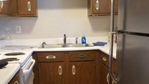 A kitchen with wooden cabinets, a stainless steel refrigerator, and a patterned rug.