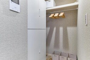 A compact storage area with a white cabinet, a clothes drying rack, and three storage bins.