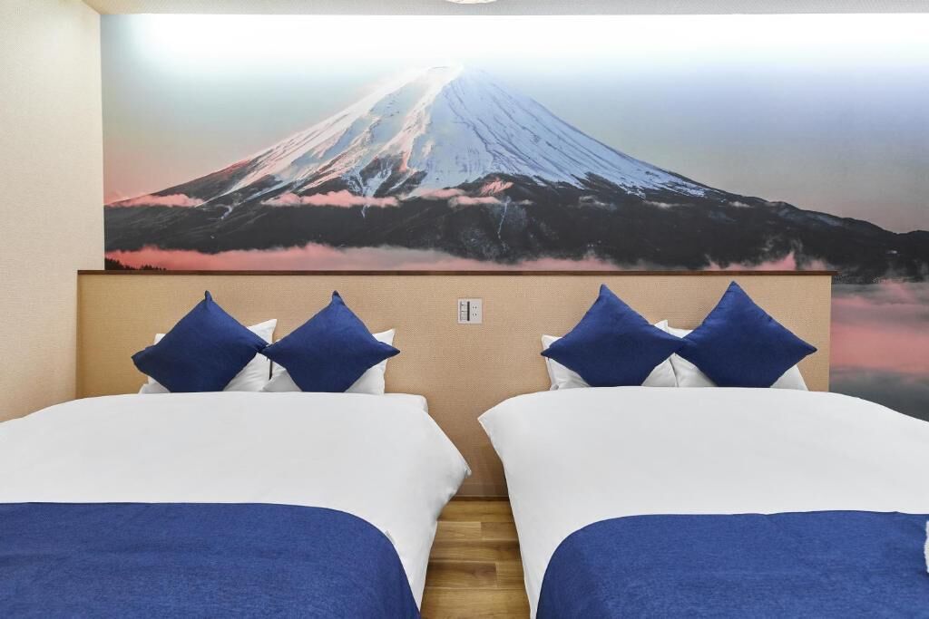 A hotel room with two beds, a large wall mural of a volcano, and a wooden floor.