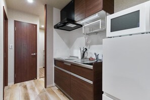 A compact kitchen with a microwave, stove, and a door leading to another room.