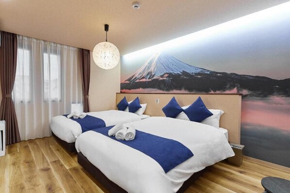 A hotel room with two beds, a large wall mural of a mountain, and a hanging light fixture.