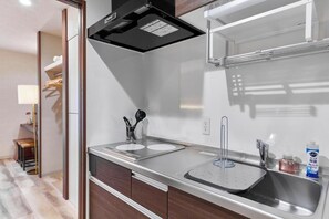 Una cocina moderna con un lavamanos de acero inoxidable, un horno empotrado y una campana extractora.