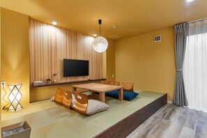 A room with a flat-screen TV mounted on the wall, a wooden dining table, and a sofa with cushions. - the hotel OSAKA bay (Osaka-shi, Minato-ku, Chikko)