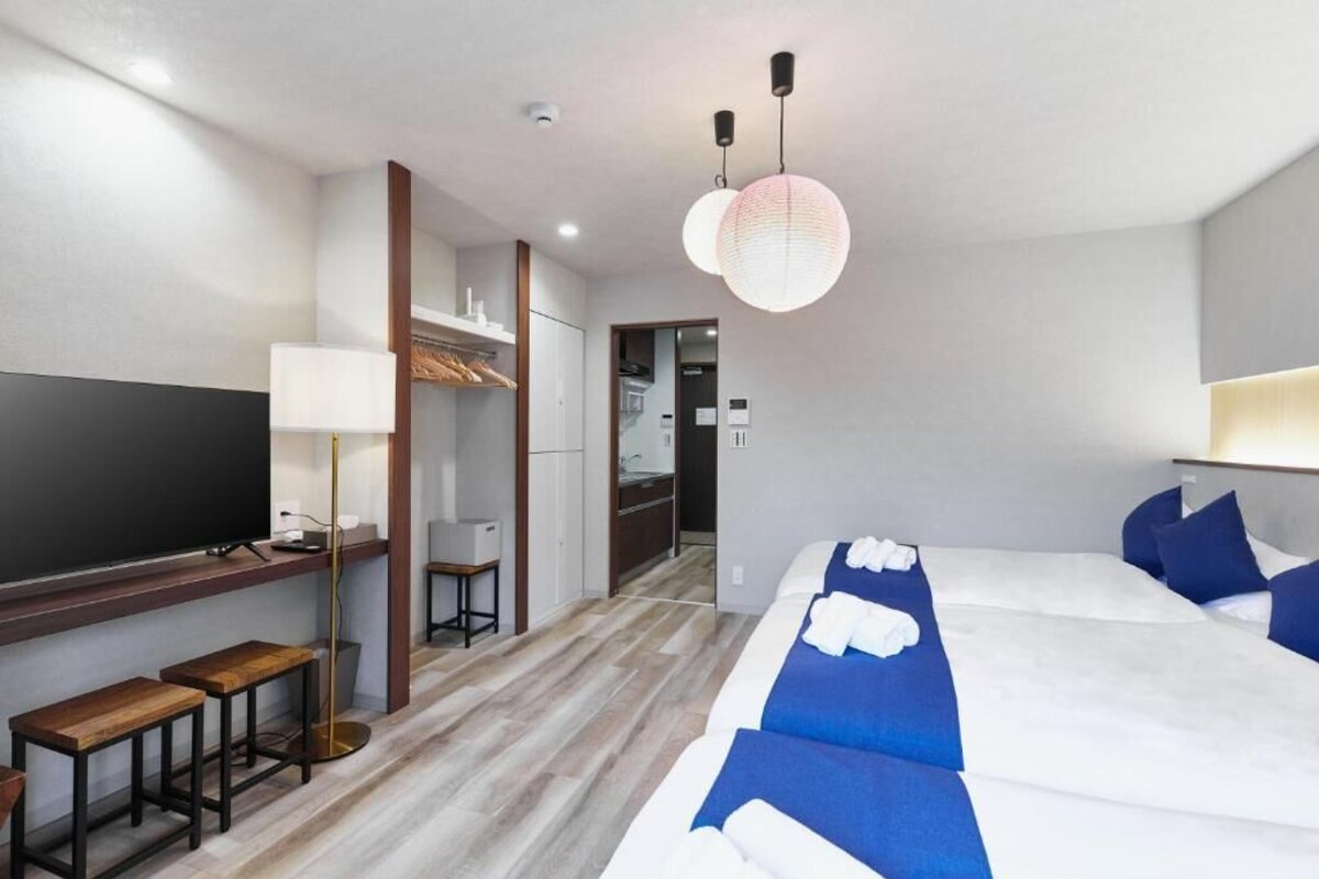 A hotel room with a bed, a desk, a TV, and a wardrobe.
