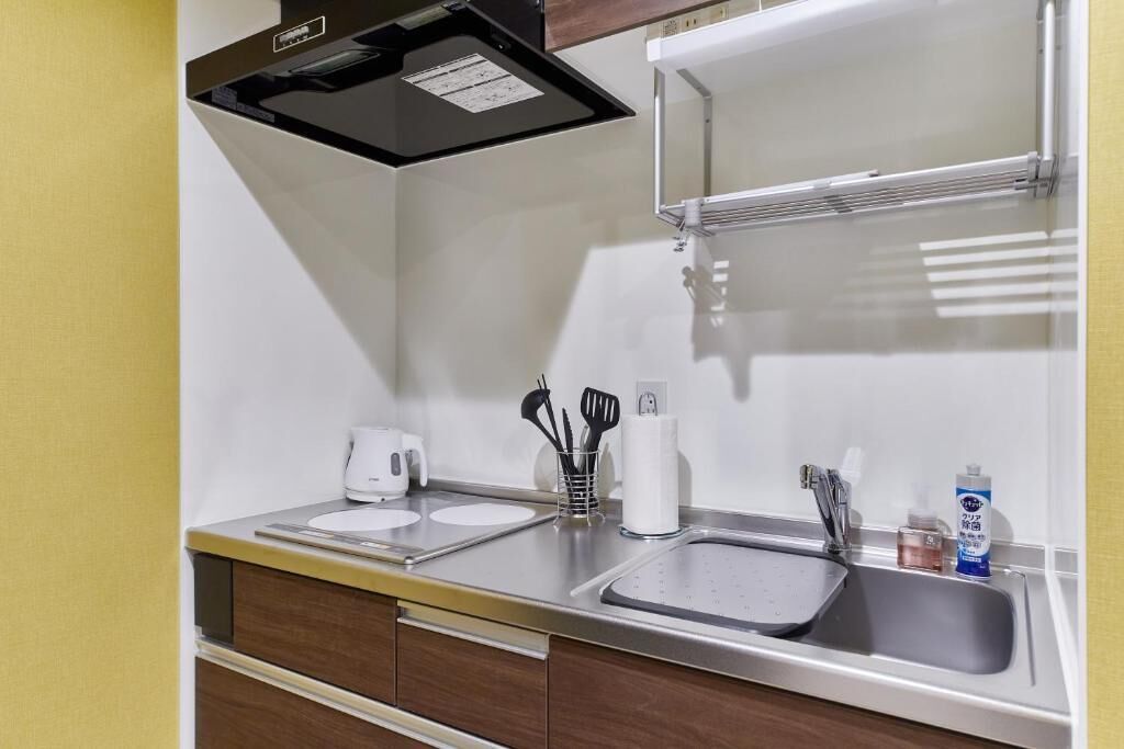Une cuisine compacte équipée d’une cuisinière intégrée, d’un évier et d’une machine à café.