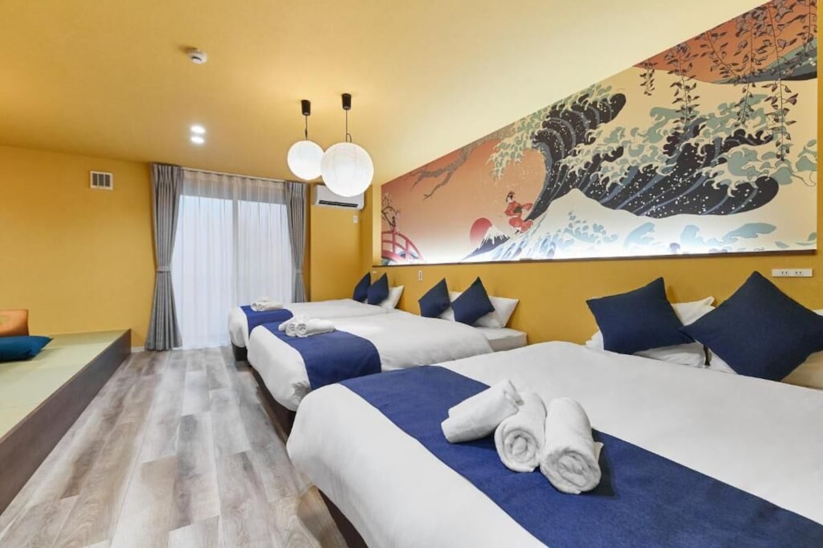 A hotel room with two beds, a large artwork on the wall, and a view of the outside.