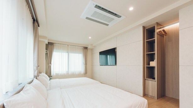 Une chambre d’hôtel avec un grand lit, une armoire, un téléviseur et un appareil de climatisation.