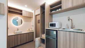 Une cuisine moderne dotée d’appareils électroménagers intégrés, de meubles de rangement en bois et d’un miroir rond placé au-dessus de l’évier.
