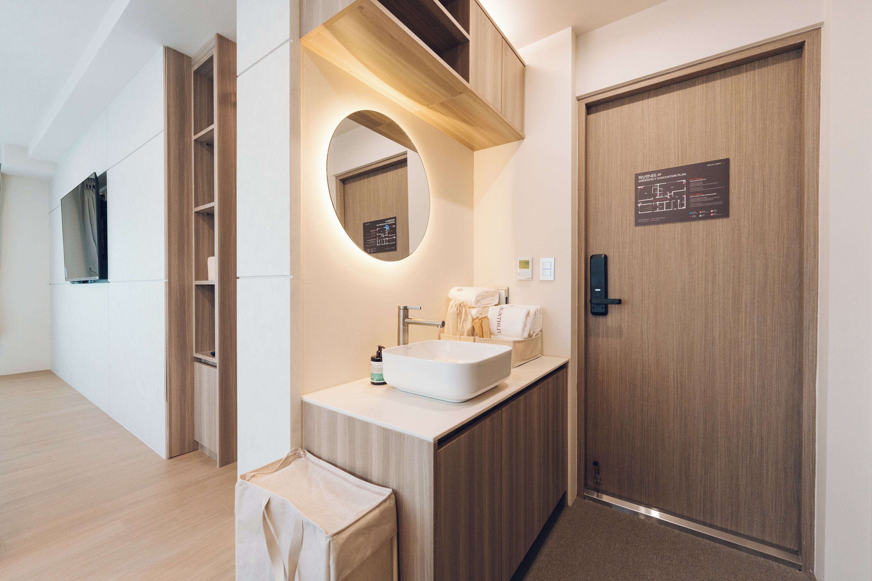 A modern bathroom with a wooden vanity, a large mirror, a sink, and a towel rack.