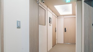 Un couloir avec des portes en bois, un luminaire au plafond et une caméra de surveillance.