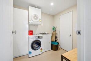 A laundry room with a washing machine, a dryer, a bucket, and a mop. - Entire home in Christchurch, New Zealand (Christchurch)