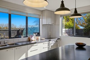 A modern kitchen with a large window, a sink, cabinets, and pendant lighting. - Entire home in Christchurch, New Zealand (Christchurch)