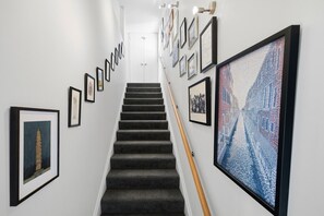 A staircase with framed artworks on the walls, leading to a door at the top. - Entire home in Christchurch, New Zealand (Christchurch)