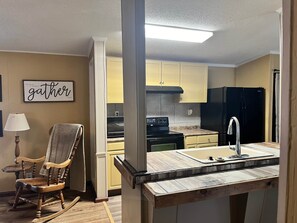 A kitchen with a wooden rocking chair, a sink, and a refrigerator. - Camp / 1097 Elm run (St. Martin Parish)