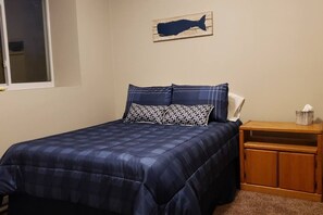 A bedroom with a bed, a nightstand, a wooden headboard, and a wall-mounted fish decoration.