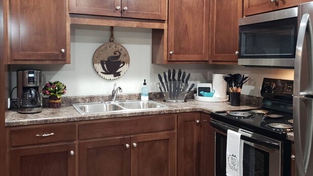 A kitchen with wooden cabinets, a stainless steel refrigerator, a coffee maker, and a microwave.