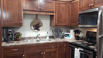 A kitchen with wooden cabinets, a stainless steel refrigerator, a coffee maker, and a microwave.
