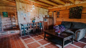 A rustic wooden interior with a dining area, a sofa, and a tiled floor.