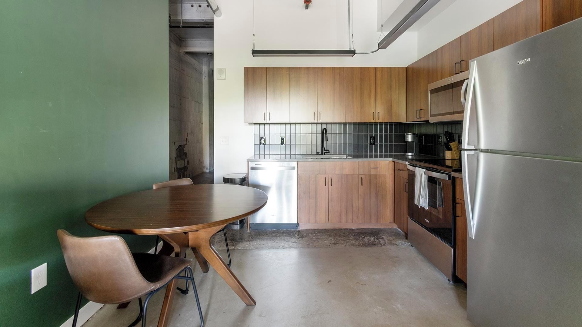 A compact kitchen with wooden cabinets, a stainless steel refrigerator, and a dishwasher.