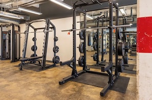 Ein Fitnessstudio mit Krafttrainingsgeräten, darunter Squat-Racks und Bänke.