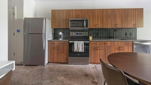 A modern kitchen with wooden cabinets, stainless steel appliances, a microwave, and a dishwasher. - Landing | Modern 1BD, Gym, Rooftop Lounge (Jacksonville)